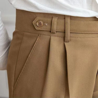 Close-up of brown pants with a button and belt buckle on a white background