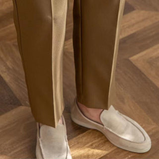 Person wearing brown pants and white loafers on a wooden floor