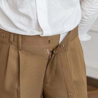 Close-up of brown pleated pants with a white shirt underneath.