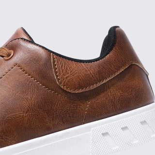 Close-up of a brown leather shoe with white sole on a light gray background