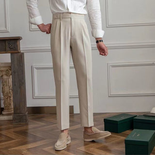 Person wearing beige pants and white shirt standing in a room with wooden floor and decorative wall panels.