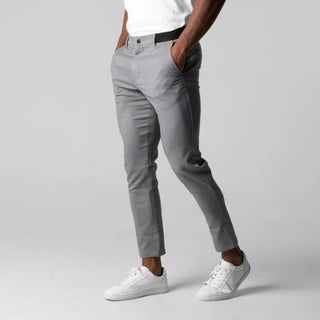 Person wearing gray pants and white sneakers on a plain background