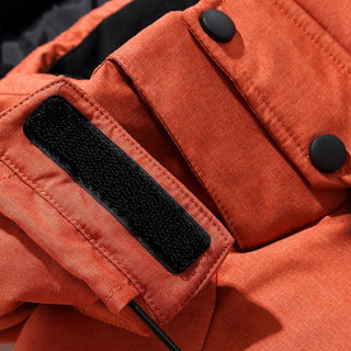 Close-up of an orange jacket with a black patch and button details.