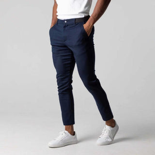 Person wearing navy pants and white sneakers on a plain background
