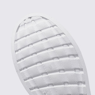 Close-up of a white shoe sole with tread pattern on a light gray background