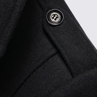 Close-up of a dark gray coat with a button on a light gray background