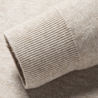 Close-up of a beige sweater with ribbed cuffs and hem.