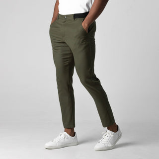 Person wearing olive green pants and white sneakers on a plain background