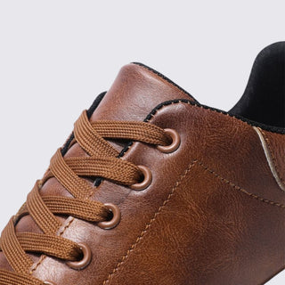 Close-up of a brown leather shoe with laces on a light gray background