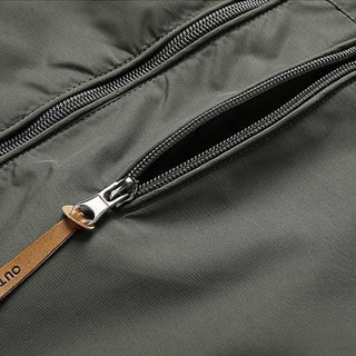 Close-up of a gray bag with a zipper and brown leather strap, featuring the brand 'Onlu'.