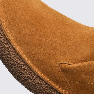 Close-up of a brown leather shoe with a textured sole on a light gray background