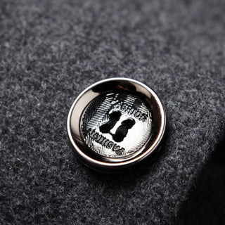 Close-up of a metallic button with engraved design on a textured fabric background