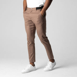 Person wearing brown pants and white sneakers on a plain background