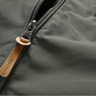 Close-up of a gray jacket with a zipper and brown leather tag.
