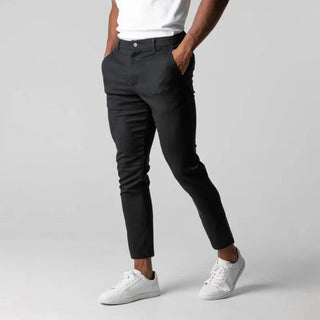 Person wearing black pants and white sneakers on a gray background