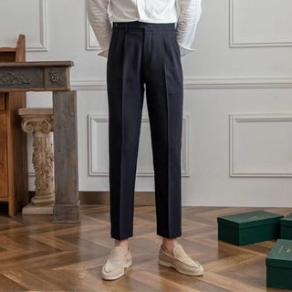 Person wearing black pants and a white shirt in an elegant room with wooden flooring and decorative elements.