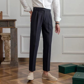 Person wearing dark trousers and a white shirt in an elegant room with wooden flooring and decorative elements.