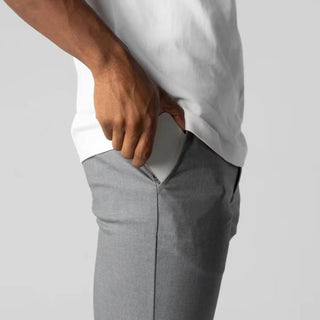 Person wearing gray pants and a white shirt on a light gray background