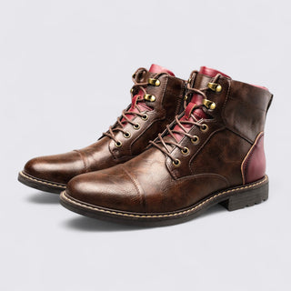 Pair of brown leather boots with red lining on a light gray background
