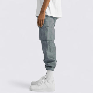 Person wearing gray cargo pants and white sneakers on a light gray background