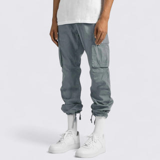 Person wearing gray cargo jogger pants and white sneakers on a white background