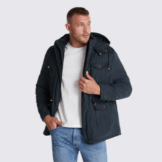 Man wearing a navy blue hooded jacket on a light gray background