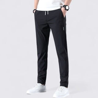 Person wearing black pants and white shoes on a light gray background