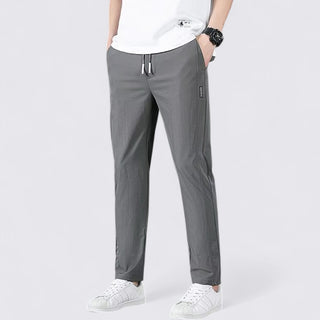 Person wearing gray pants and white sneakers on a white background