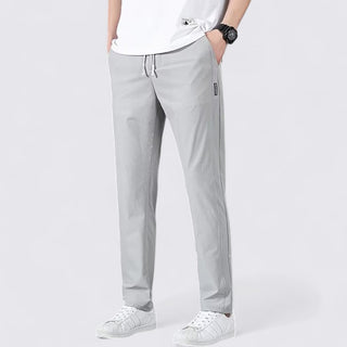 Person wearing light gray pants and white sneakers on a white background